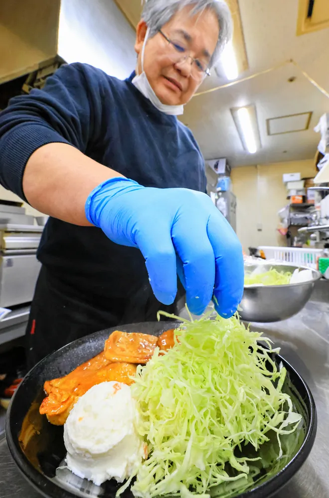 定食にキャベツの千切りを添える釧路市の飲食店「喫茶ポラリス」の古宮一弥オーナー。キャベツなど食材費の高騰が悩みだ（大島拓人撮影）