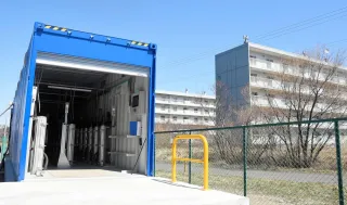 グリーン水素を貯蔵したボンベを収納する祝津町の建屋（左）。集合住宅の近くに拠点が設置されるのは全国的にも珍しい＝10日