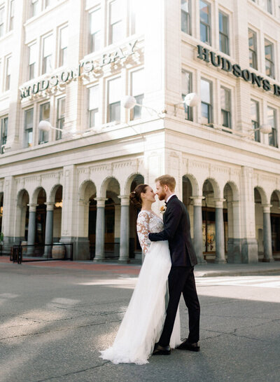 Bride and Groom embracing in downtown Calgary with the Hudson venue in the distance.