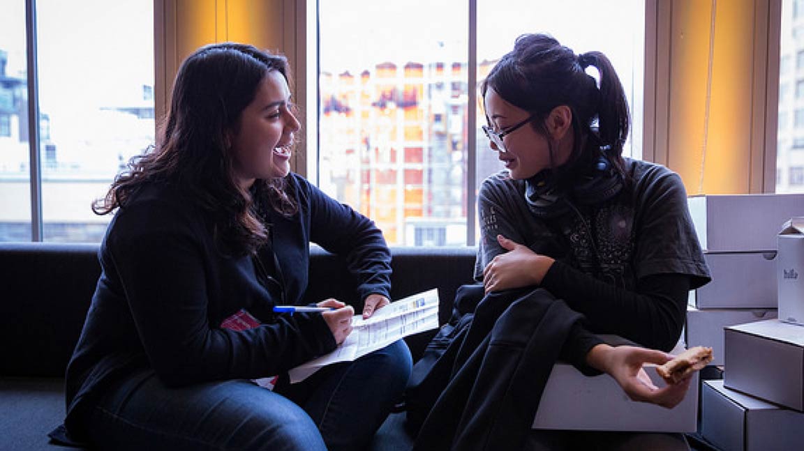 Two people cheerfully discussing notes