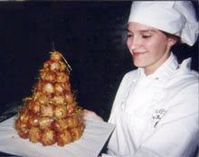 Una chef profesional pâtissier presenta un tradicional croquembouche.