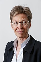 Portrait d'une femme aux cheveux châtins, portant des lunettes.