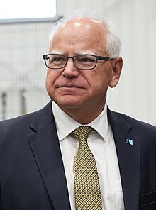 Walz stands with the new Minnesota flag pinned to the lapel of his suit.