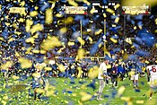 Blue and yellow confetti and people on a football field