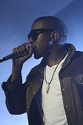 Kanye West tampil mengenakan kacamata hitam.