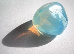 Tyndall effect in an opalite: it scatters blue light making it appear blue from the side, but orange light shines through. Opal is a gel in which water is dispersed in silica crystals.