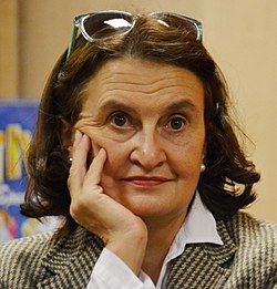 close-up of Eva Holubová supporting her chin with her hand, looking left of camera