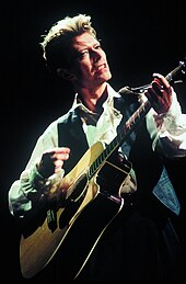 A man holding a guitar with his back turned