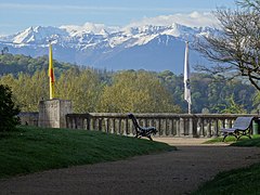 Photo d'un paysage montrant au premier plan un jardin public et au fond des montagnes enneigées.