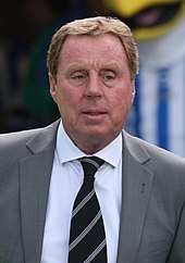 The upper body of a sandy haired man with a face with relaxed muscle tone. He is looking into the distance to his left. He is wearing a grey jacket and dark, striped tie.