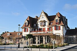 Vue en couleur d'une gare en arrière-plan d'un parking.