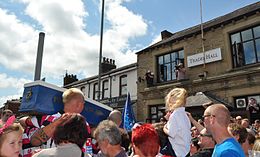 A crowd in bright clothing and football kits, carrying a coffin marked "PRESTON NORTH END".