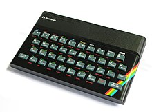 A black, rectangular, and plastic console with "Sinclair" in raised, thin, and wide lettering. A keyboard is built into the unit. Its keys are light gray and Chicklet-sized with white lettering. Near each key are three abbreviated functions written in all capital letters and in three colors: white, green, and red.