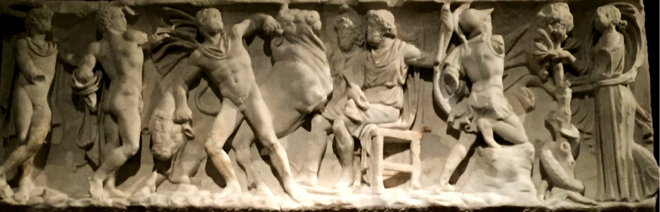 Haut-relief montrant un homme au centre assis sur une chaise et entouré de plusieurs hommes impliqués dans des activités physiques.