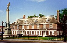 Large, two-story building with a statue in front