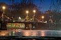 Boston Public Garden Foot Bridge at night, 2007. The bridge is illuminated by lampposts, and several people are standing on it.