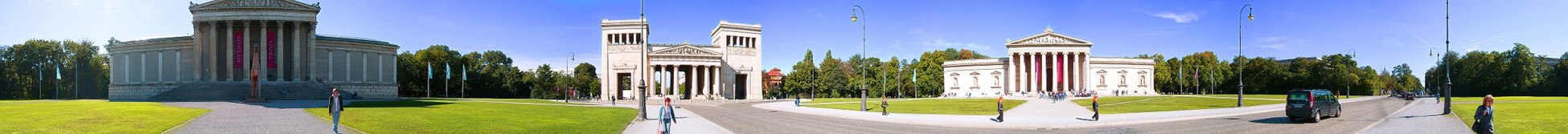 Panorámica de 360º de la Königsplatz (Múnich). Es un amplio espacio rodeado por edificios de arquitectura neoclásica (entre los que está el de la Gliptoteca, primero por la derecha). Su impresionante entorno fue utilizado como escenario de acontecimientos políticos por los reyes de Baviera y posteriormente por el nazismo. Los desfiles atravesaban el eje longitudinal pasando por debajo de los Propíleos (edificio del centro).