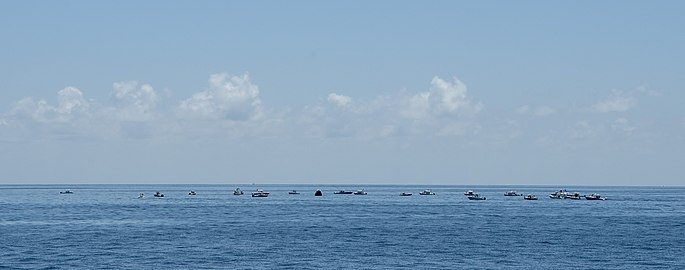 Large numbers of private boats create a circle around the Endeavour capsule.