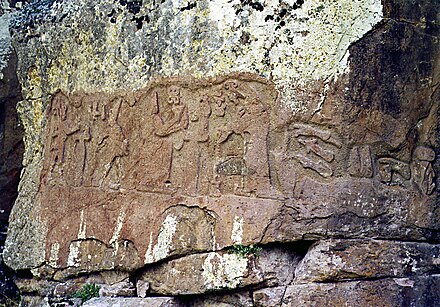 Photographe d'un bas-relief sur rocher montrant cinq personnes.