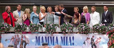 Smiling cast members standing in a row for a group photo.