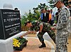 A memorial in Korean and English commemorating the Hill 303 massacre, with flowers being laid by Korean and American soldiers