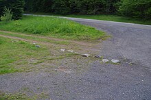 Pierres umbones dépassant encore du sol au niveau d'un chemin longeant la route départementale.