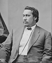 Formal photographic portrait of a sitting mustached man