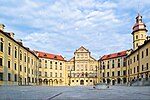 Palace courtyard surrounded with yellow buildings. A well in the middle.