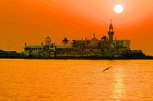 A white building with one minaret on an island seen at sunset