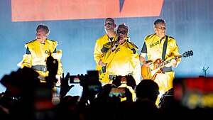 Devo onstage, wearing their trademark bright yellow radiation suits