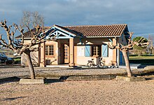 Photo de la mairie d'Espaon éclairé par le soleil couchant : petit bâtiment de plein pied, la porte est protégée par un porche. Deux fenêtres sont situées de part et d'autres de la porte, cerclées de briques. Celle a droite à des volets bleus. Le toit du bâtiment est en tuiles.