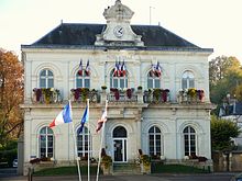 photographie d'un bâtiment à étages pavoisé de drapeaux tricolores.