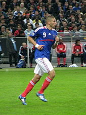 Photo de Karim Benzema, de profil, en train de courir sur le terrain vêtu du maillot de l'équipe de France.