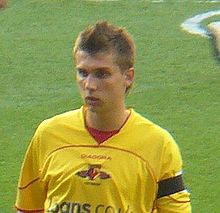 A footballer with spiky hair in a yellow shirt