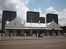 A Dutch colonial-style house with the flag of the South African Republic flying outside.