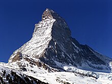 Sommet pyramidal glacé sur fond de ciel bleu foncé.