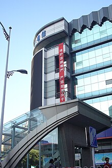 A vertical, red propaganda banner hanging high on a modern hotel with Chinese writing: "维护法律尊严，严惩犯罪分子")