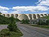 A large concrete multiple arch buttress dam straddles a gorge, withholding water.