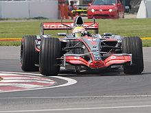 A silver Formula One car driving around a corner.