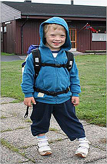 A boy wearing a jacket and a backpack