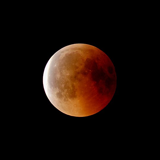 Der am 27. Juli 2018 bei Vollmond während einer Mondfinsternis aus dem Kernschatten der Erde tretender Blutmond. Der gegenüber dem Fixsternhimmel nach links ziehende Vollmond wird an der linken Seite bereits wieder vom direkten Sonnenlicht getroffen; ungefähr einer Stunde später hatte der Mond den Erdschatten verlassen.