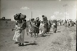 Women carrying bags while walking with men and children