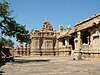 An ornately carved stone building seen across a paved courtyard