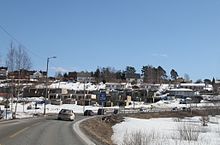 Foto einer Straße, die durch einen Ort führt. Die Landschaft ist verschneit.