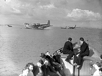 Passagers sur un canot, rejoignent un hydravion imposant.