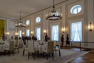 Großer Saal mit Tischen für ein Dîner