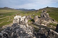 View from the top a hill of a grassy valley and rocks in the foreground