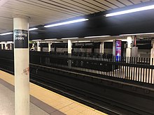 The three platforms of the Bowling Green station as seen from the northbound side platform, with the southbound island platform in front and the abandoned shuttle platform in the rear. There is a fence along the edge of the southbound platform.