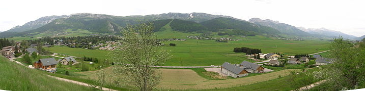 Panomara d'un bourg et ses alentours, avec chaine de montagnes en fond, depuis un point culminant.