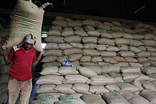 Behind him, thousands of bags are stacked in rows.